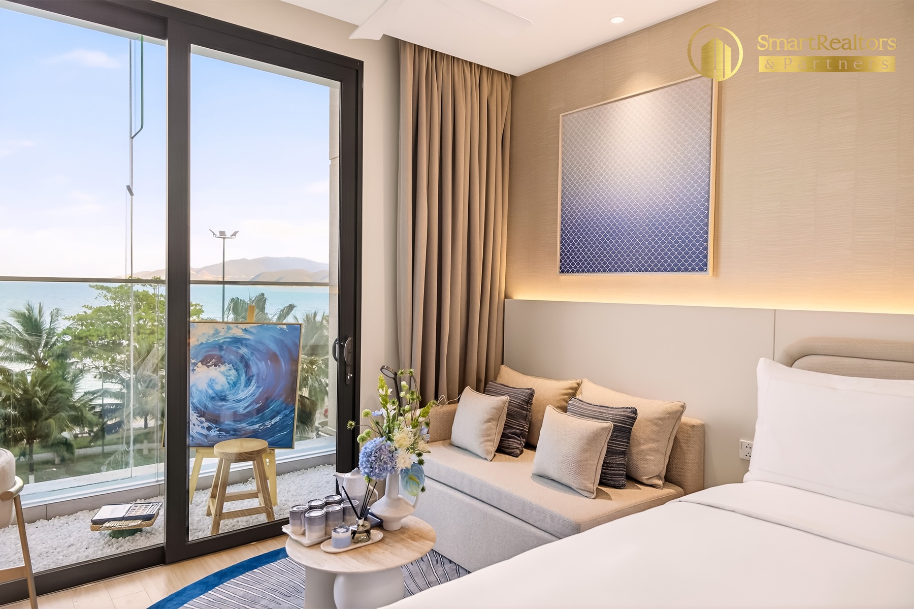 Căn hộ mẫu Studio: giường đôi, ghế daybed và cửa kính ra ban công hướng biển