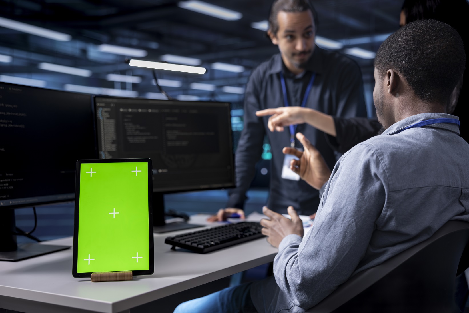 Practice Multiethnic team using green screen tablet to oversee servers used for managing databases. Diverse staff members collaborating while working on mockup device in data center storing information